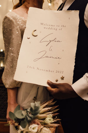 A wedding welcome sign on handmade cotton rag paper with crescent moon and star details in gold leaf. 