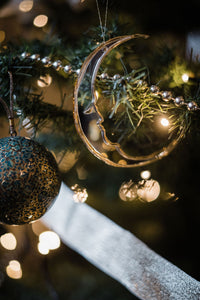 A crescent moon shaped bauble hanging in a tree