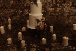 handmade gold moon phase cake charms on a wedding cake surrounded by candles