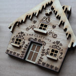 Load image into Gallery viewer, A wooden gingerbread house shaped ornament with personalised family name and hand carved design.
