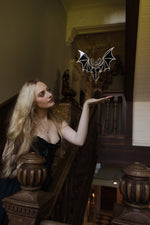 Load image into Gallery viewer, A bat shaped mirror floating in a stairwell of an old manor house
