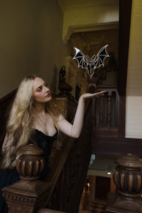 A bat shaped mirror floating in a stairwell of an old manor house