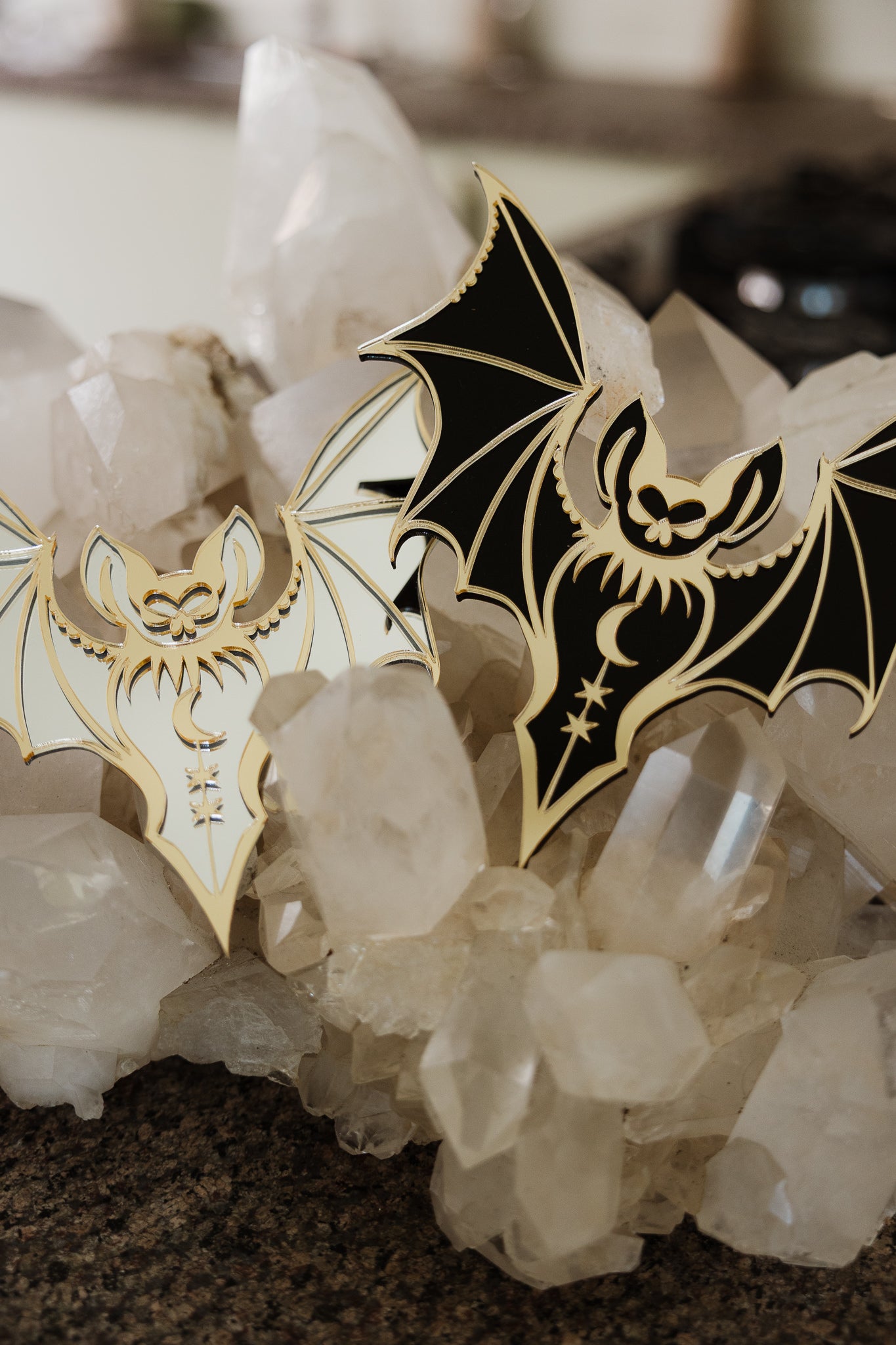 2 bat shaped mirrors laying on a bed of crystals