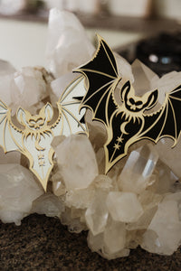 2 bat shaped mirrors laying on a bed of crystals