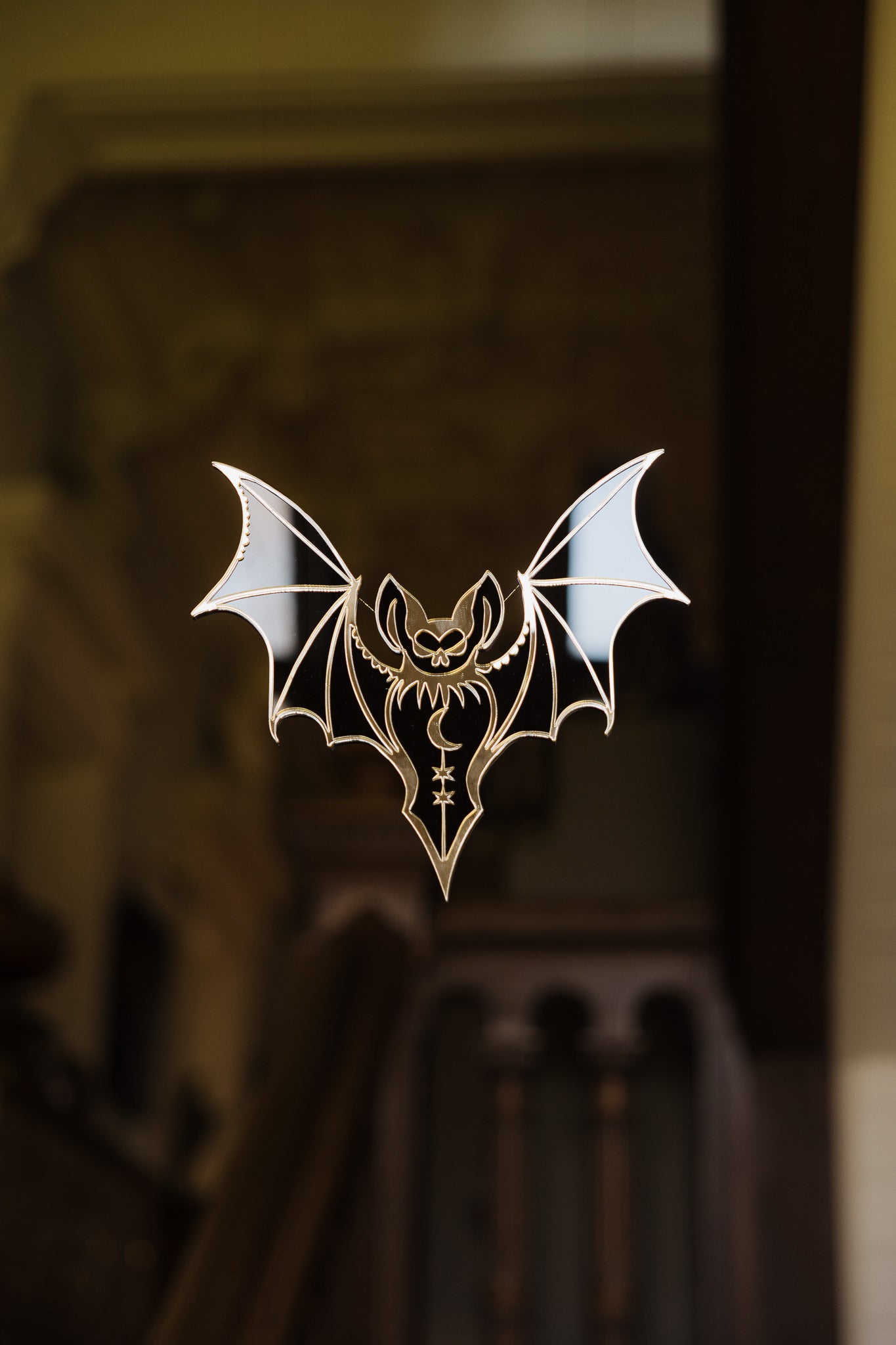 A black and gold bat shaped mirror floating in a stairwell