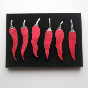 A photo taken from above of six chilli pepper shaped ornaments in a gift box.