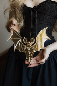 A gold bat shaped mirror held in hands