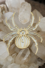 Load image into Gallery viewer, A gold spider shaped mirror laying on a bed of crystals
