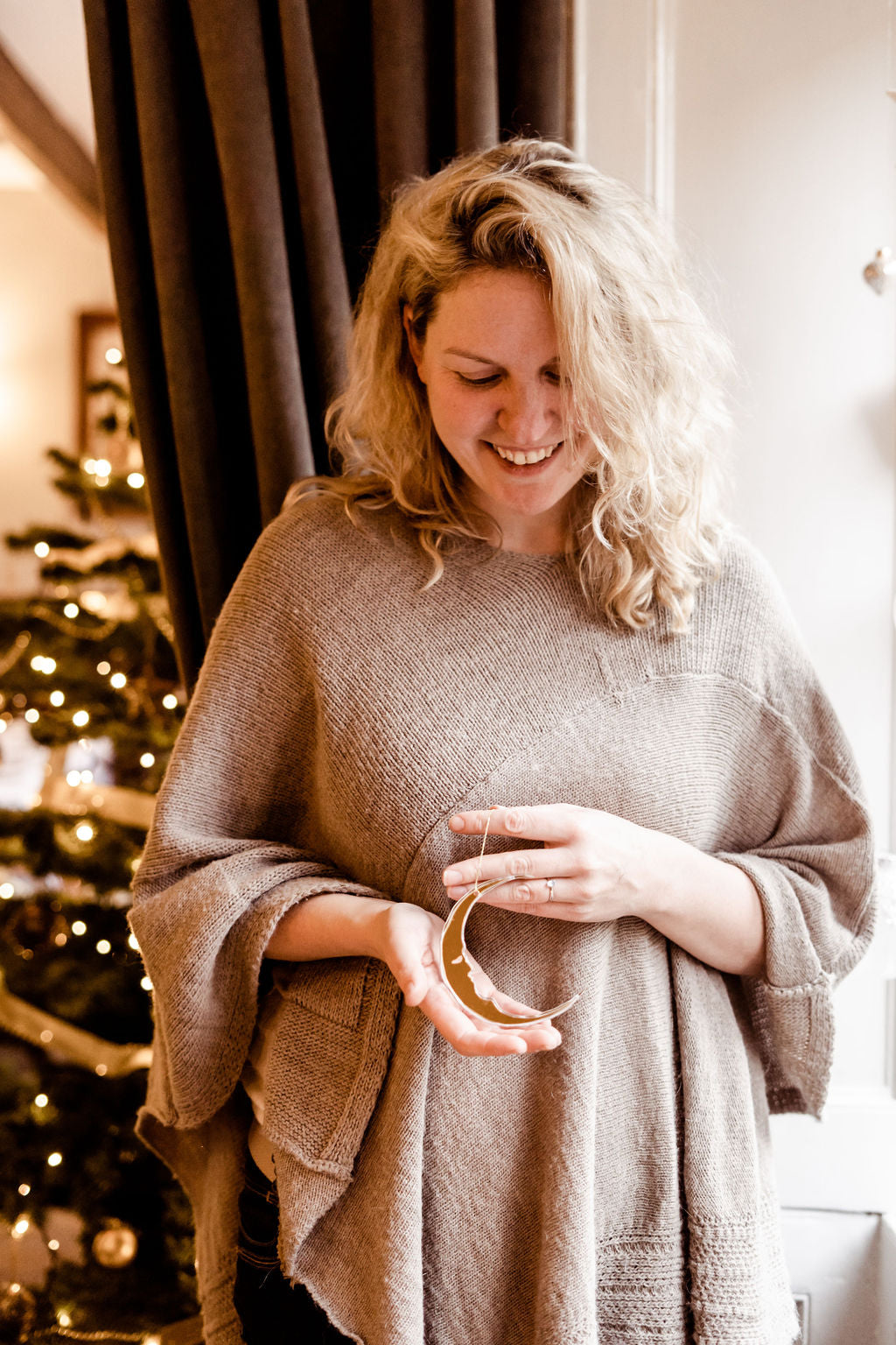 A crescent moon shaped bauble held in hands of woman.