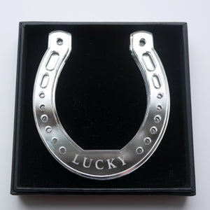 A silver horseshoe shaped ornament with the word lucky in a giftbox
