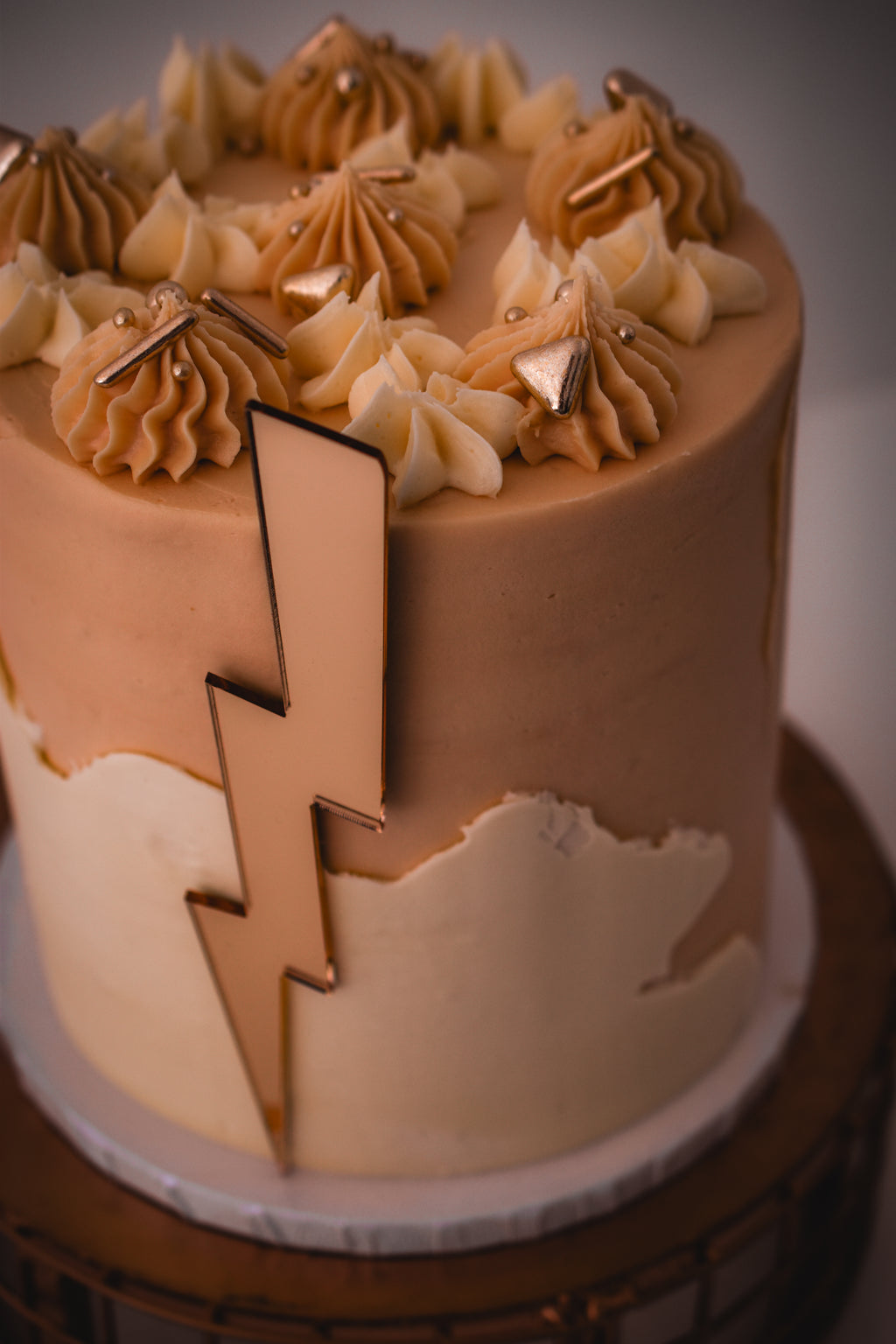 A lightening bolt shaped cake topper on the side of a cake.