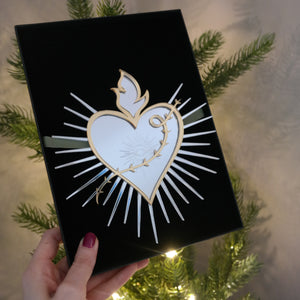 Sacred heart shaped mirrored christmas tree topper in gift box next to christmas tree.