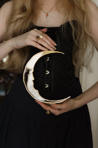 A gold and silver crescent moon mirror held in hands