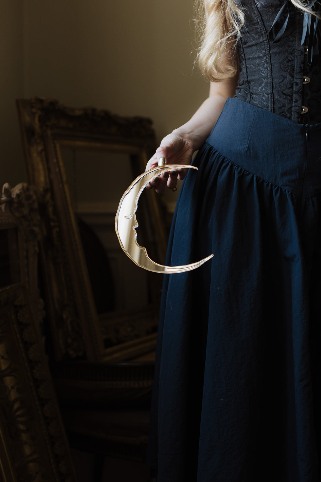 A gold moon mirror held in the hallway of a old manor house