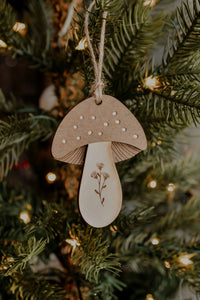 An mushroom shaped wooden ornament hanging in a christmas tree.