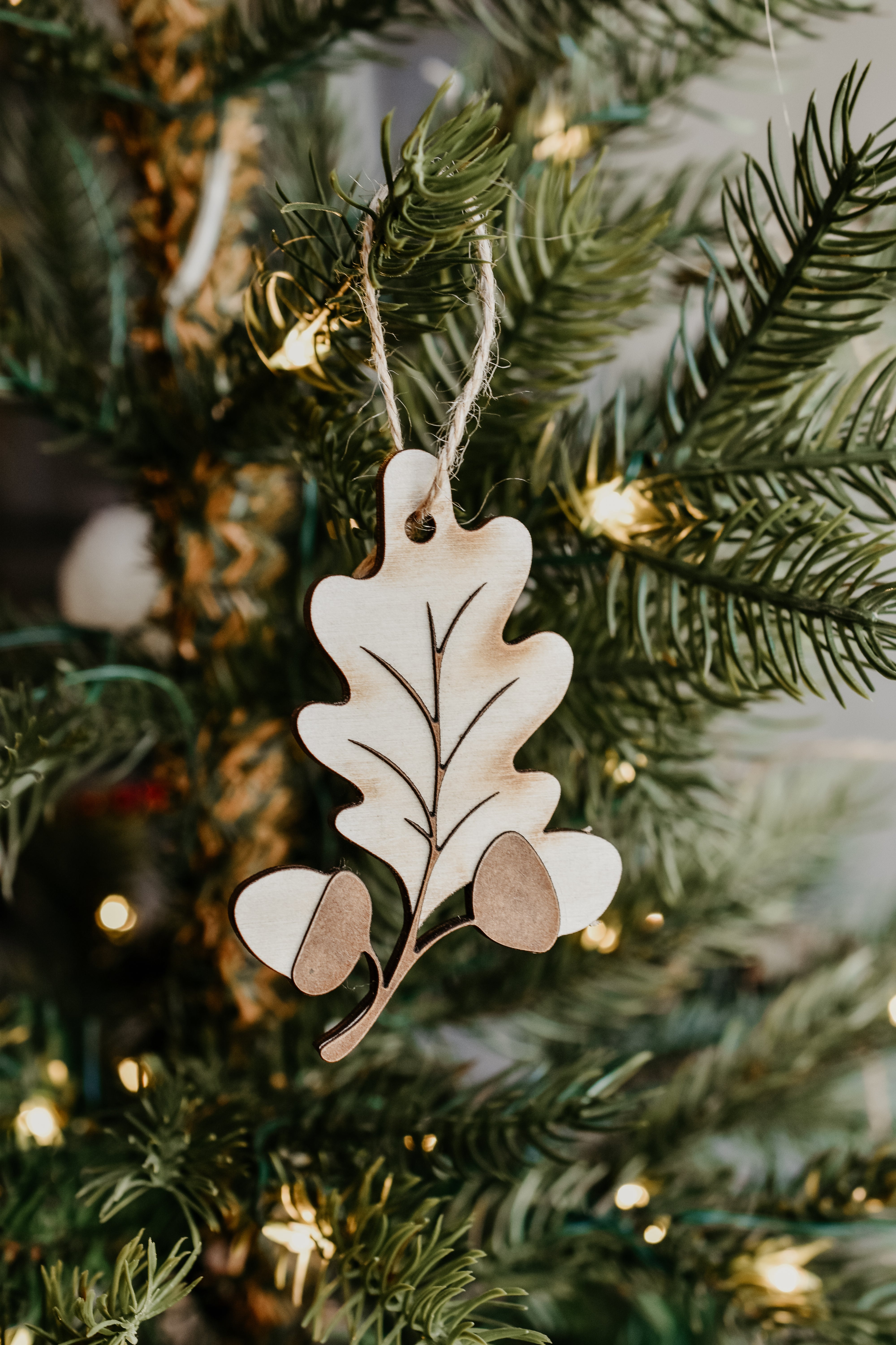 A leaf shaped wooden ornament hanging in a christmas tree.