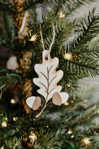 A leaf shaped wooden ornament hanging in a christmas tree.