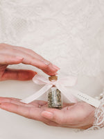 Load image into Gallery viewer, Wedding place name printed on pink bow attached to jar held in hands.
