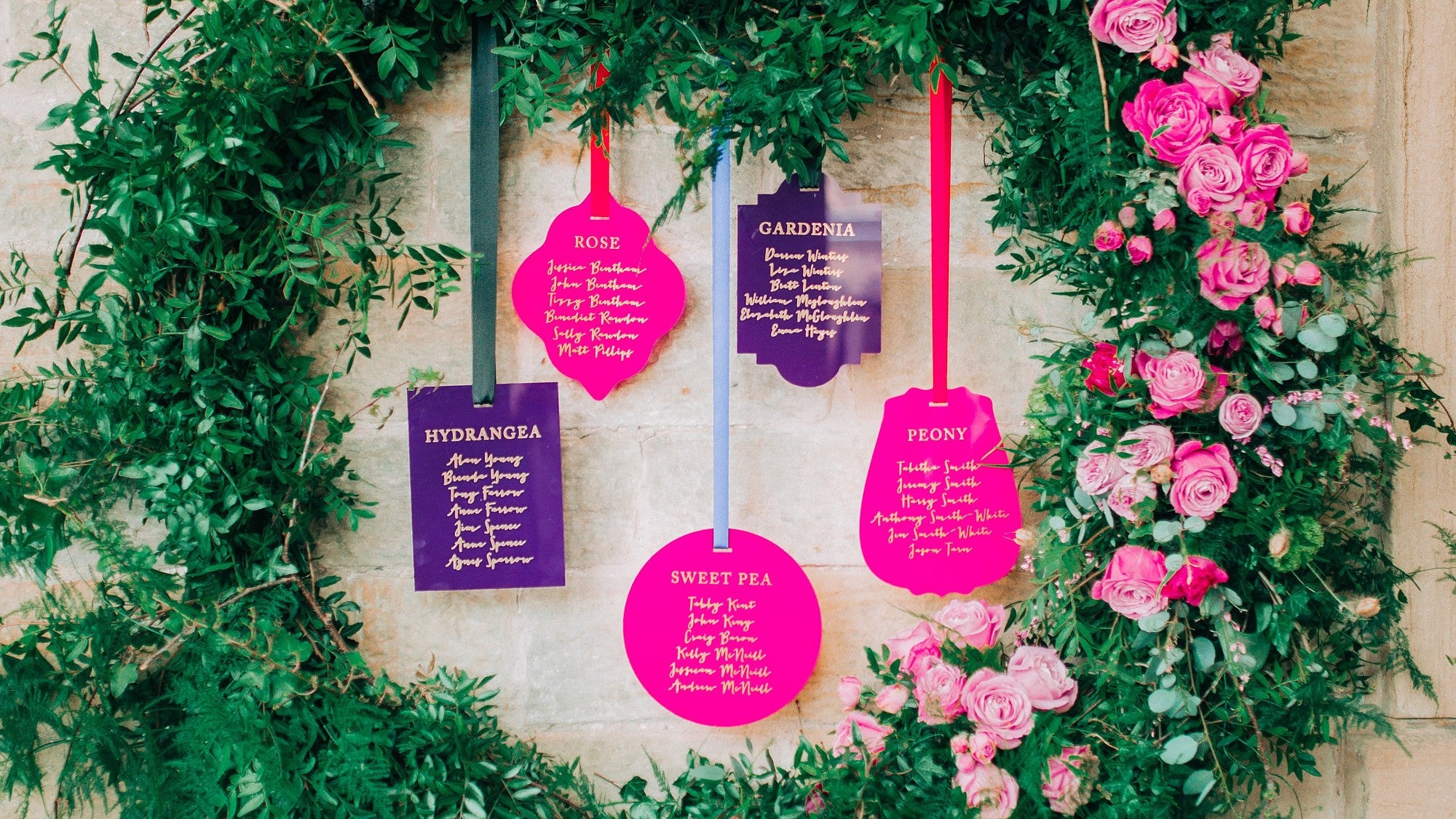 A purple and pink acrylic hanging seating plan display for a wedding