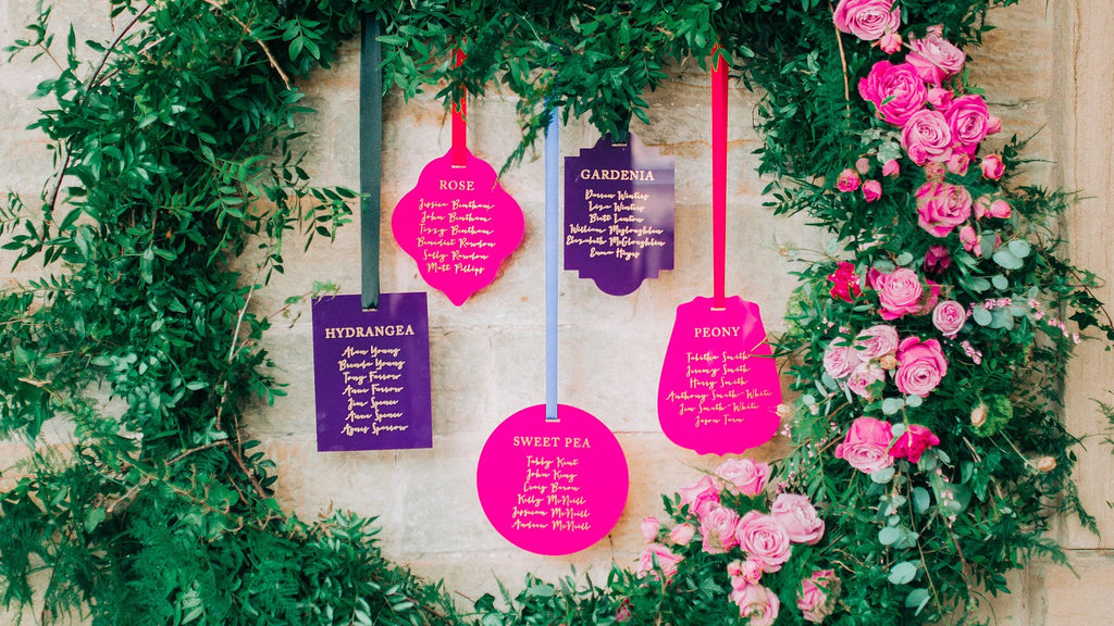 A purple and pink acrylic hanging seating plan display for a wedding