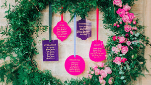 A purple and pink acrylic hanging seating plan display for a wedding