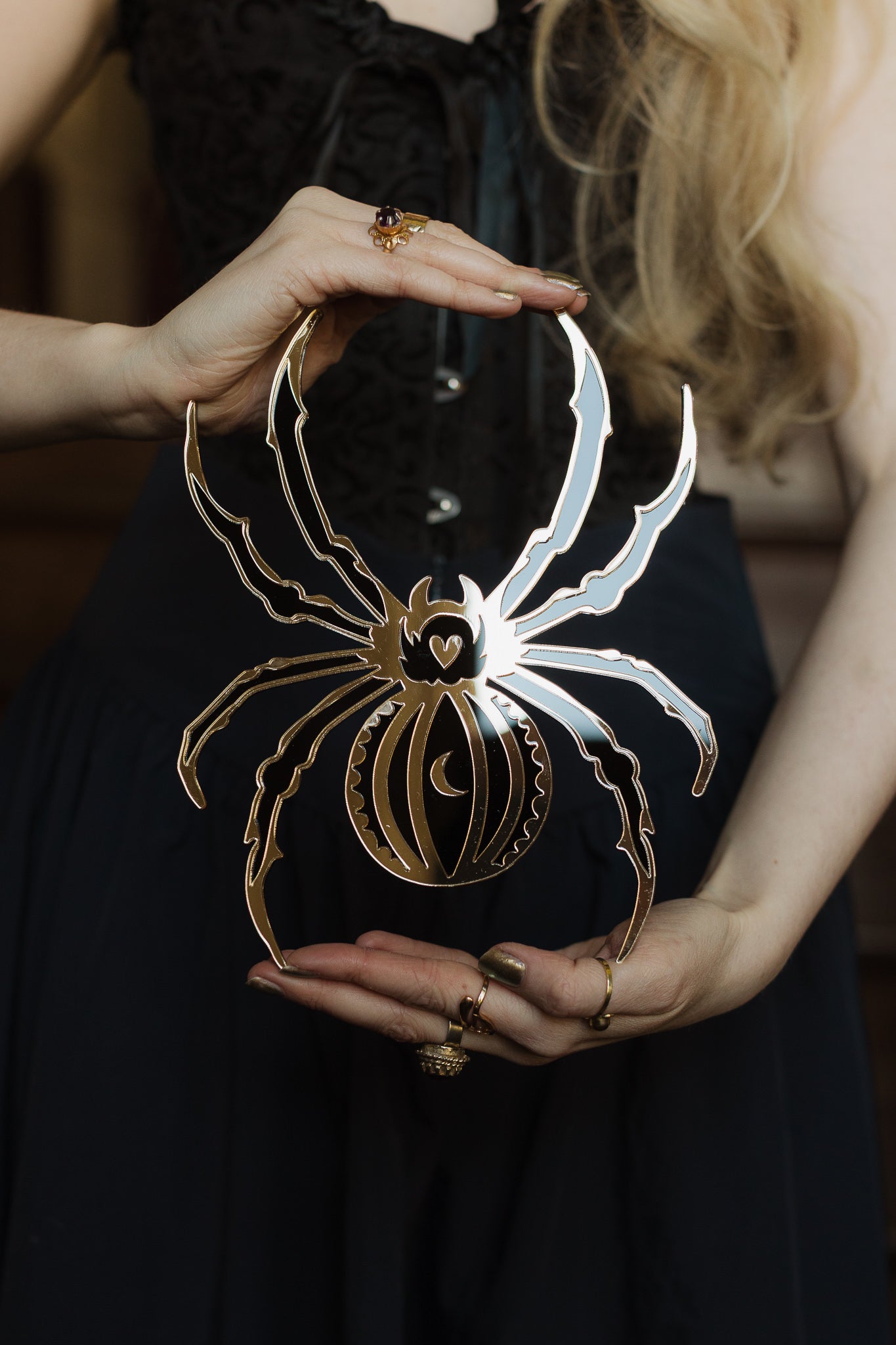 A black and gold spider mirror held in hands