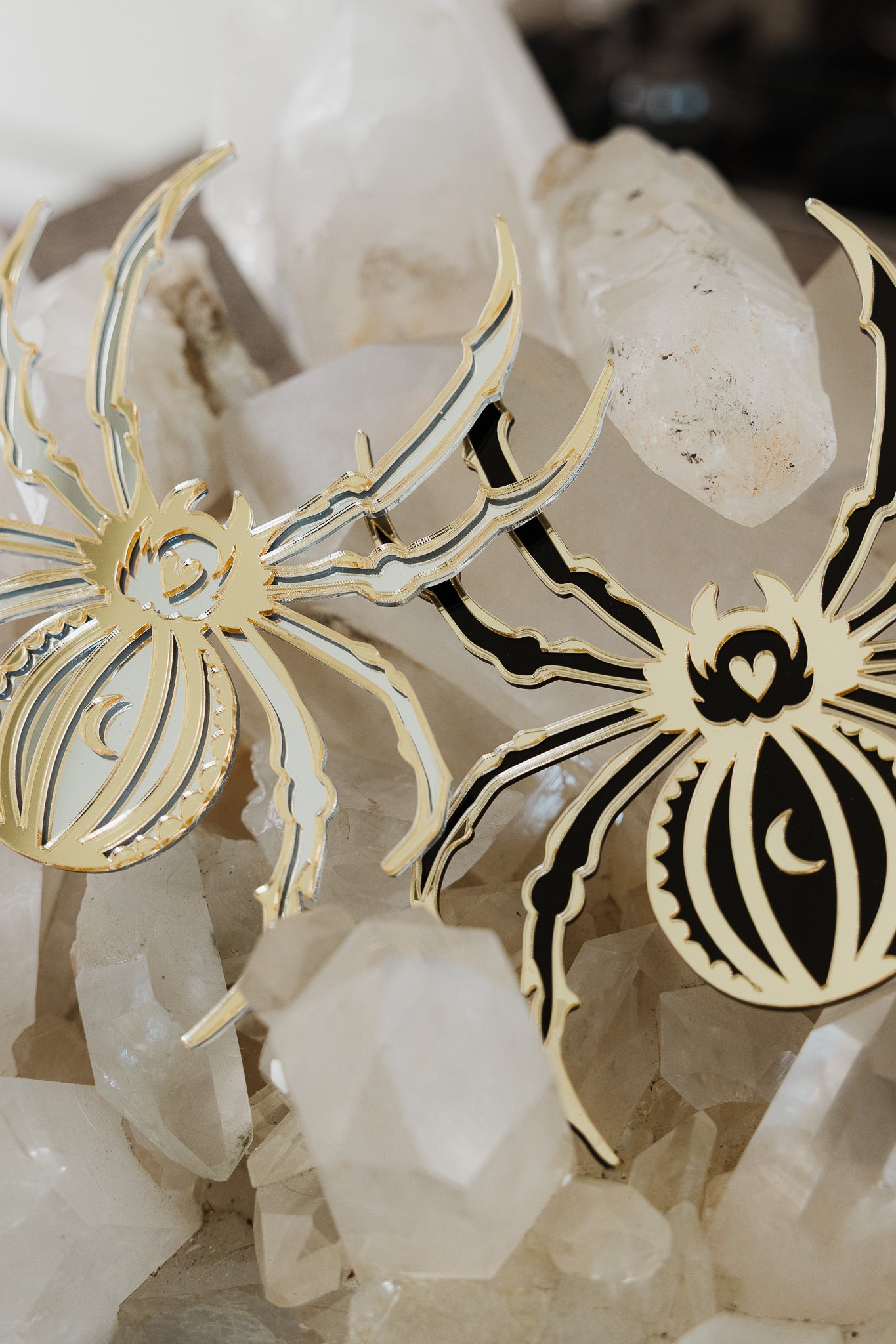 2 spider shaped mirrors laying on a bed of crystals
