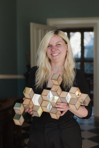 A blonde woman holding a Rhombille tiling wall decoration