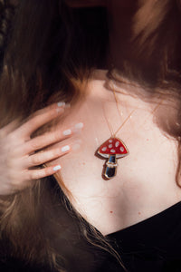 A red, white and silver toadstool shaped necklace with acrylic and mirror.