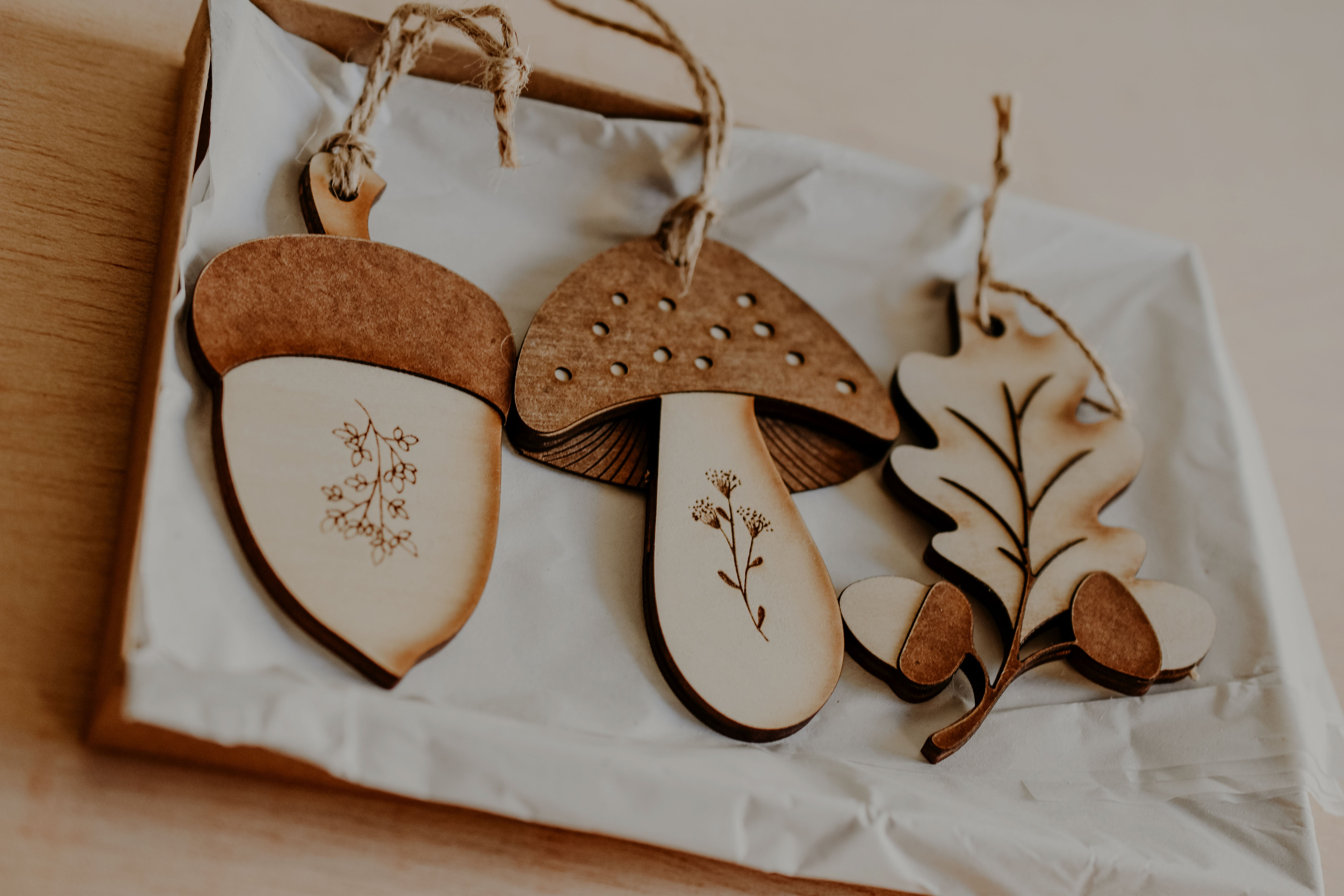 3 woodland themed decorations in the shape of a leaf, acorn and mushroom handmade from wood in a gift box.