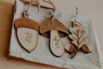 Load image into Gallery viewer, 3 woodland themed decorations in the shape of a leaf, acorn and mushroom handmade from wood in a gift box.
