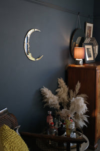 crescent moon shaped mirror on dark wall in home.
