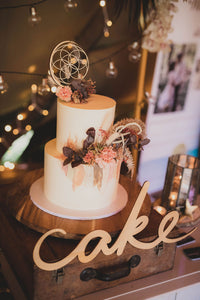 Sacred Geometry wooden cake topper on stand with wooden sign saying cake.