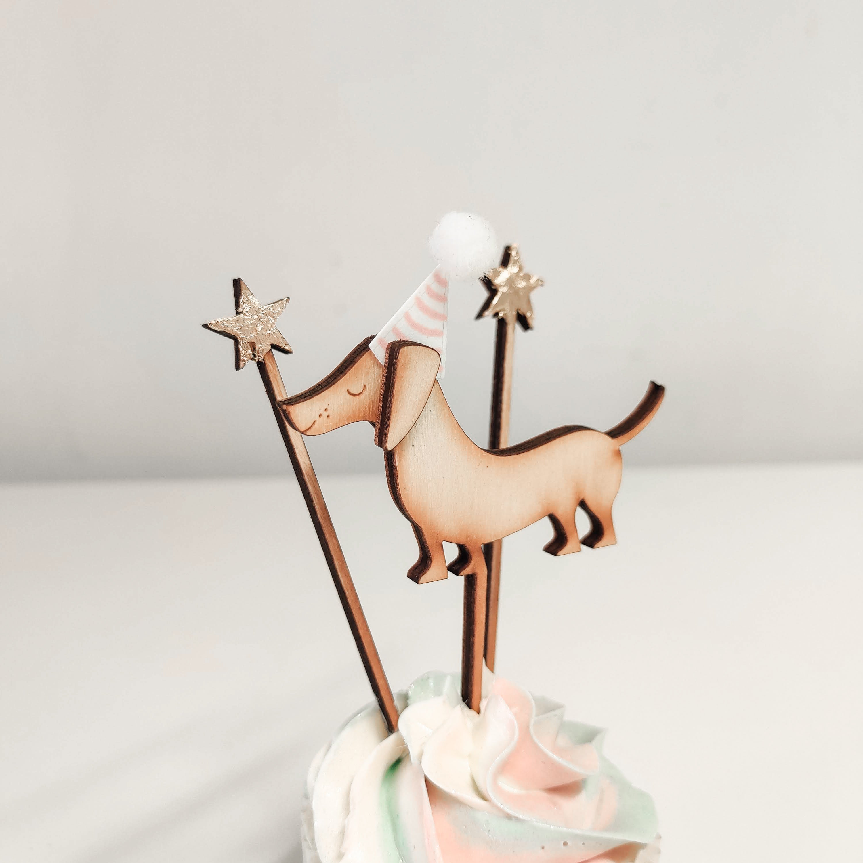 A handcrafted wooden sausage dog cupcake topper with party hat