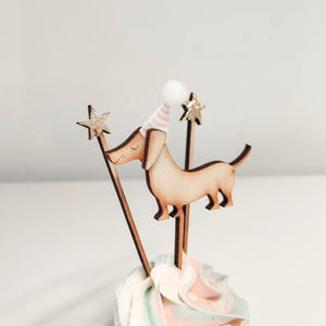 A handcrafted wooden sausage dog cupcake topper with party hat