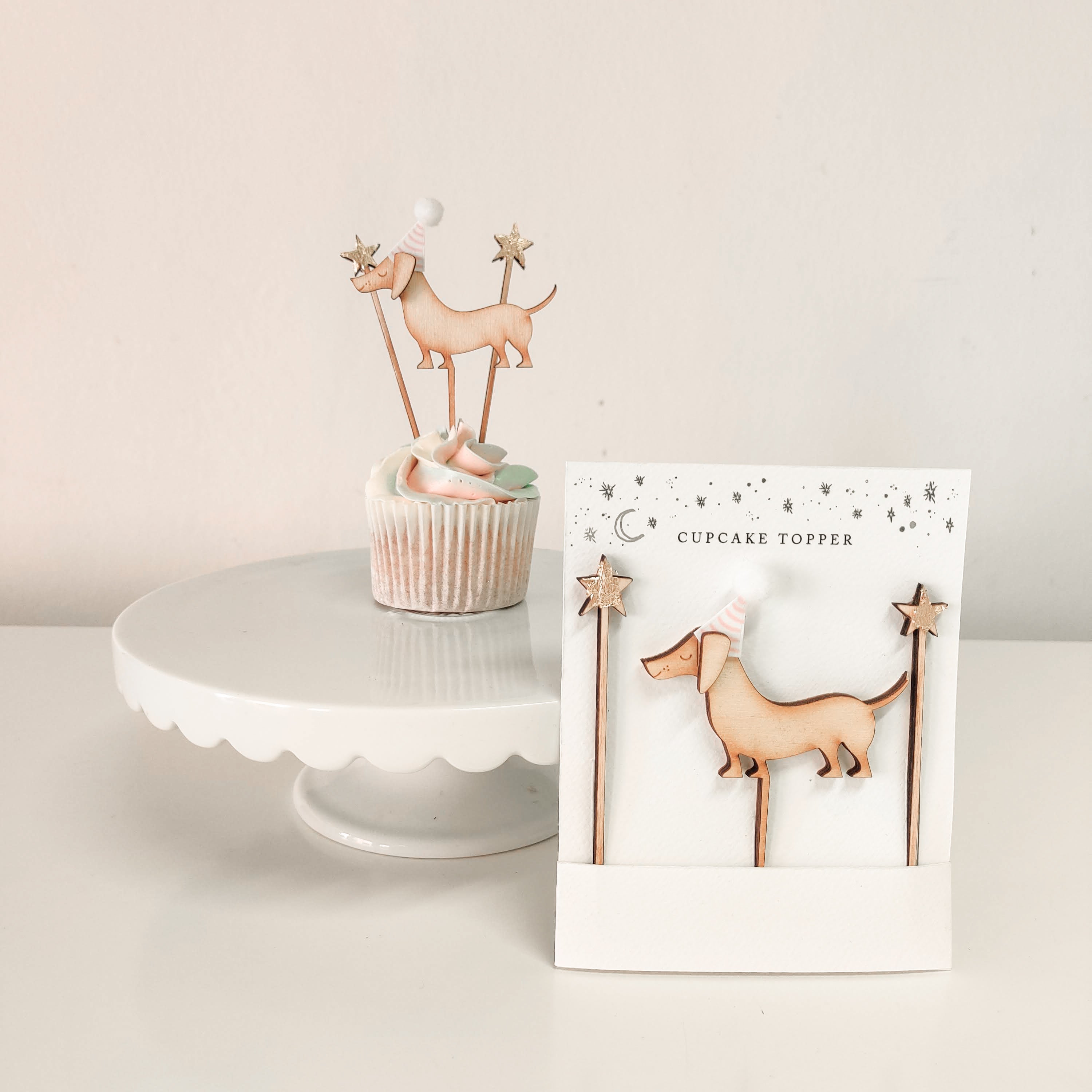 A handcrafted wooden sausage dog shaped cupcake topper with stars