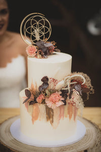 Sacred Geometry wooden cake topper on white cake with flowers
