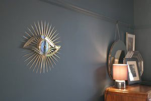 All seeing eye shaped mirror on wall in home.
