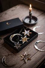 Load image into Gallery viewer, Star and crescent moon shaped christmas baubles in gift box on table next to candle
