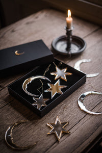 Star and crescent moon shaped christmas baubles in gift box on table next to candle