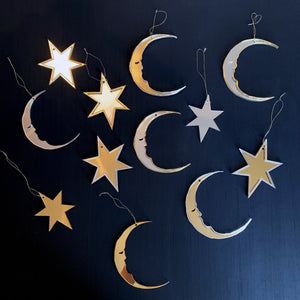 Star and crescent moon shaped christmas baubles laid out on table.