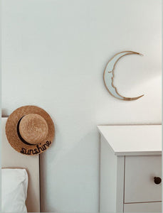 crescent moon shaped mirror next to beach hat with words sunshine