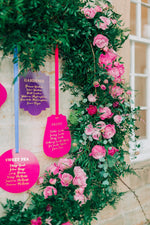 Load image into Gallery viewer, A purple and pink acrylic hanging seating plan display next to roses for a wedding
