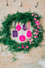 Load image into Gallery viewer, A purple and pink acrylic hanging seating plan display with wreath for a wedding
