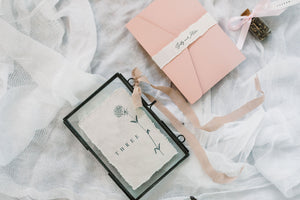  handmade rag paper table number with floral design next to envelope 