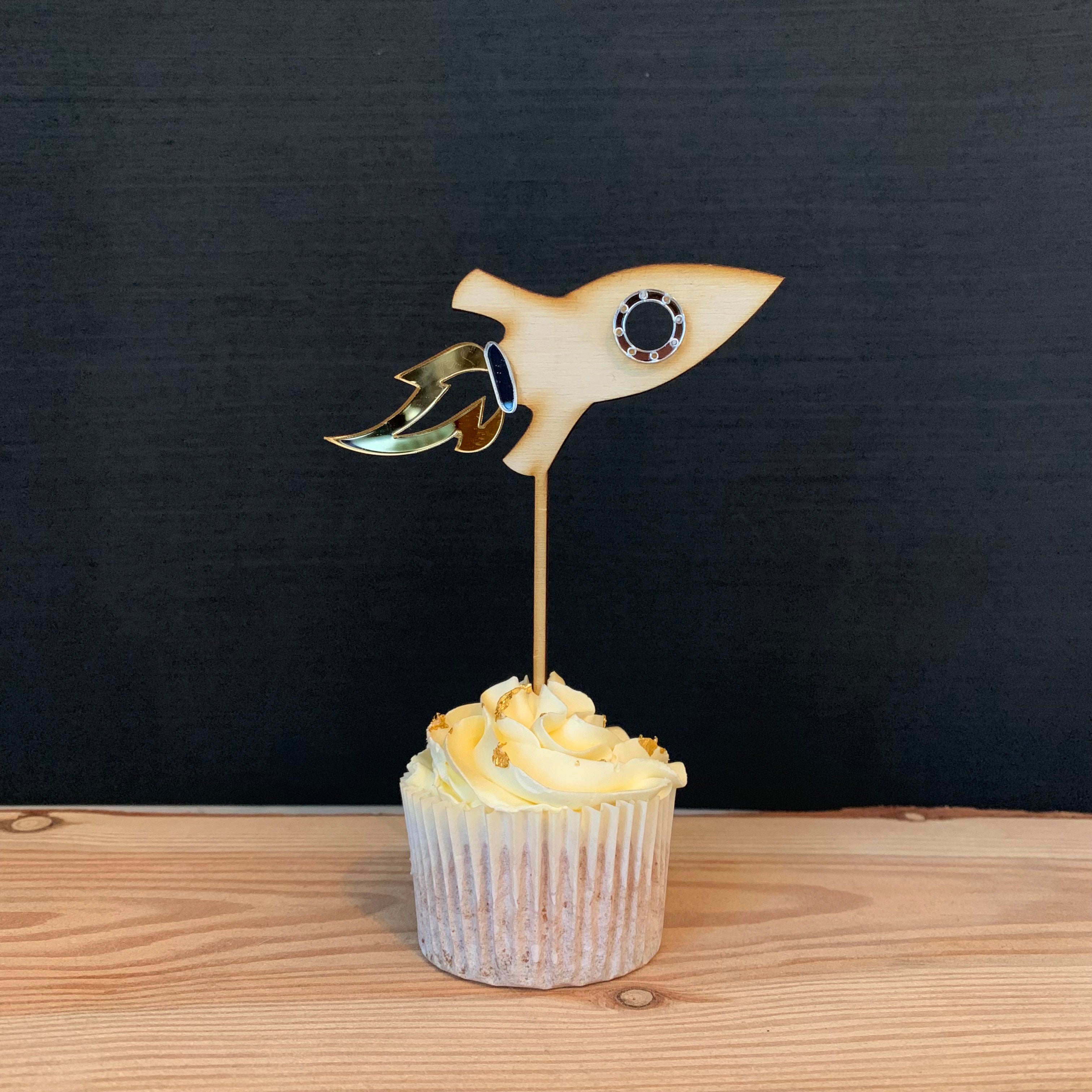 wooden rocket shaped cake topper on a cupcake.