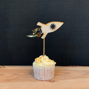 wooden rocket shaped cake topper on a cupcake.