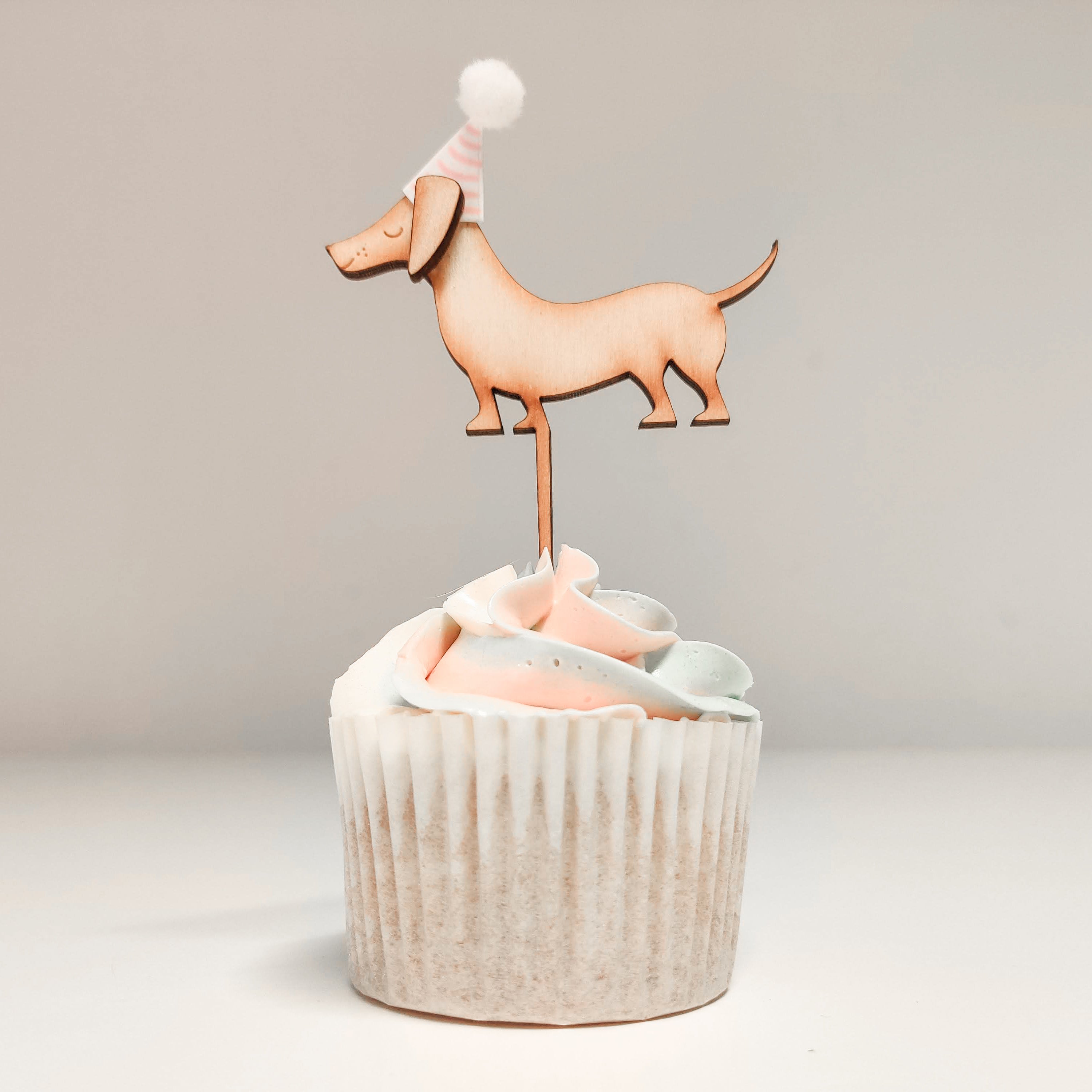 A sausage dog shaped cupcake topper on a cupcake
