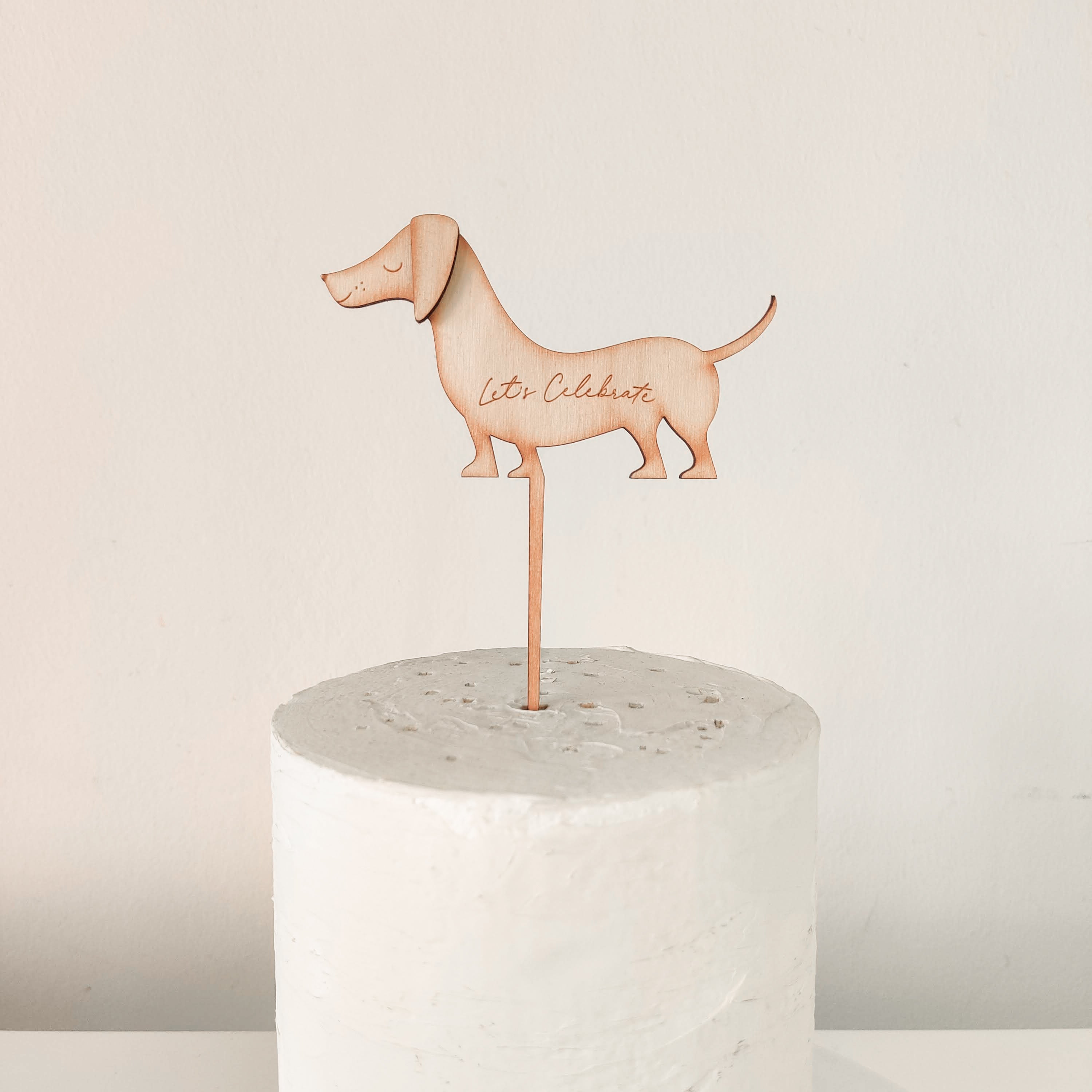 A wooden engraved sausage dog shaped cake topper