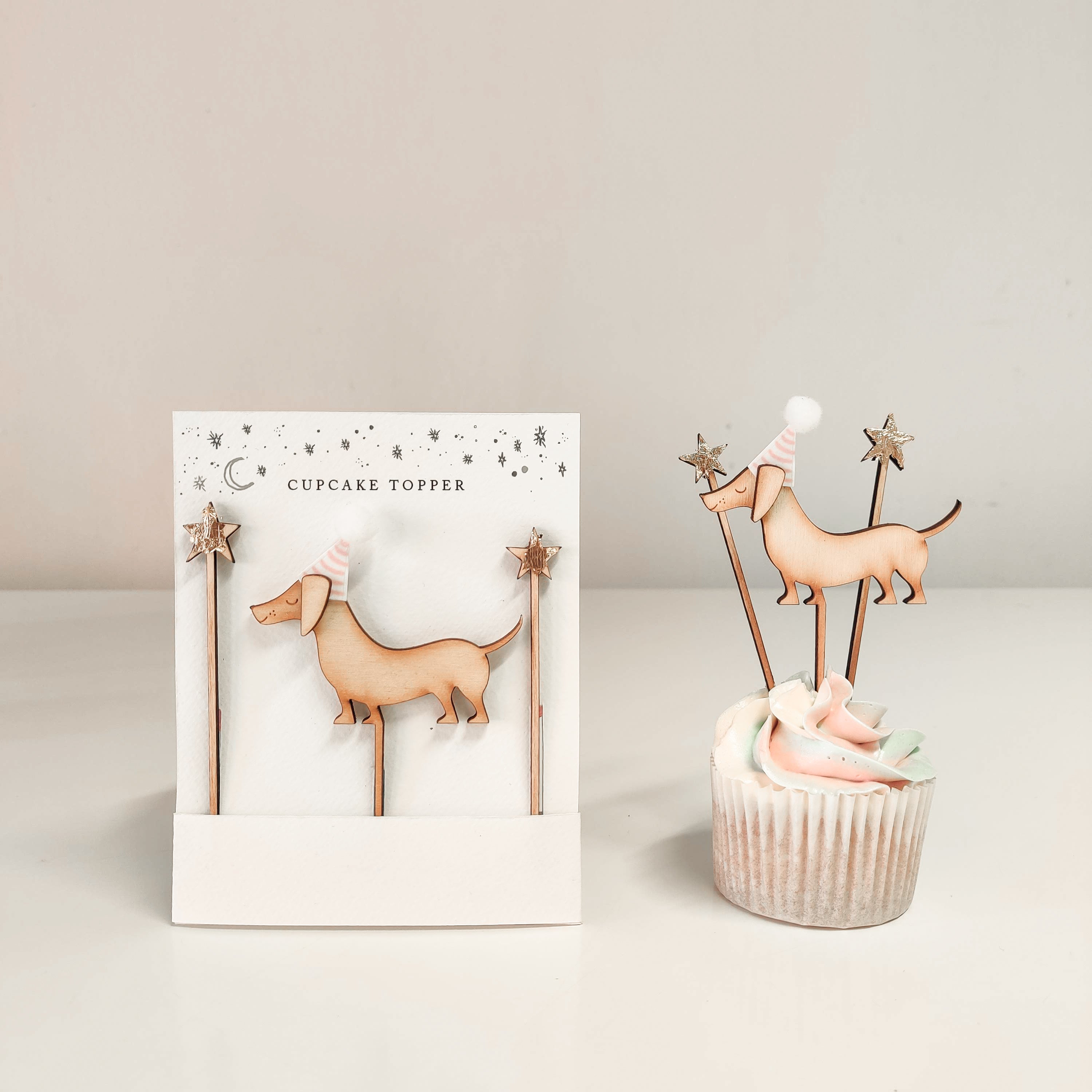 A wooden sausage dog and star shaped cupcake topper  